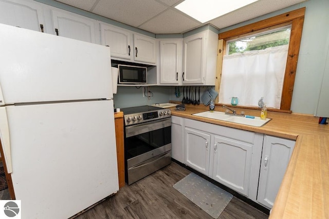 kitchen featuring electric stove, sink, white cabinetry, black microwave, and white fridge