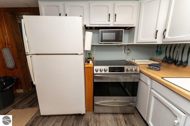 kitchen with stainless steel electric stove, white fridge, dark wood-type flooring, and white cabinets