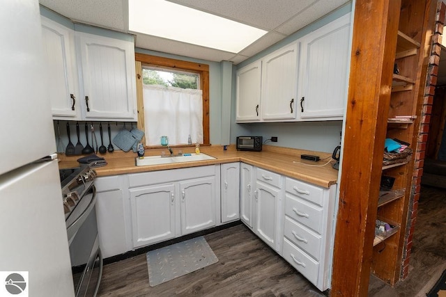 kitchen with dark hardwood / wood-style floors, white cabinetry, sink, white refrigerator, and stainless steel range