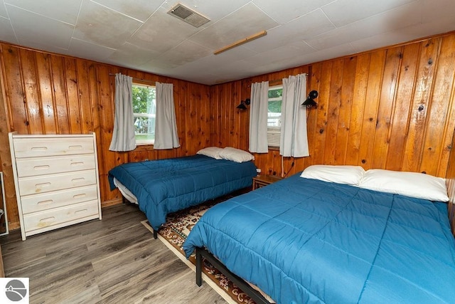 bedroom with wooden walls and dark hardwood / wood-style flooring