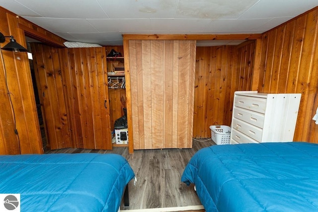 bedroom with dark hardwood / wood-style flooring and wood walls