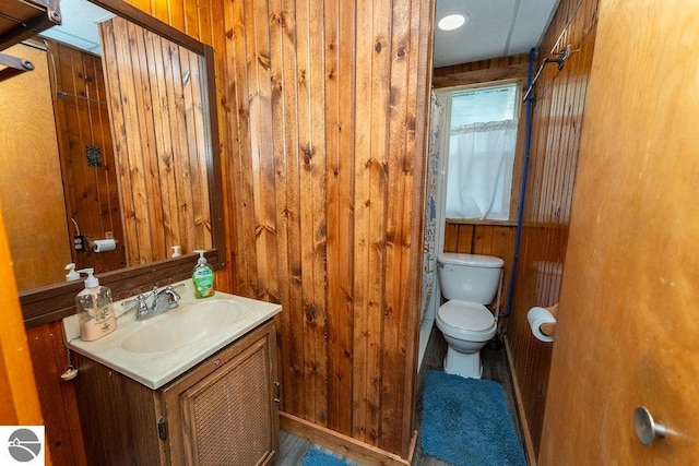 bathroom with vanity, wooden walls, and toilet