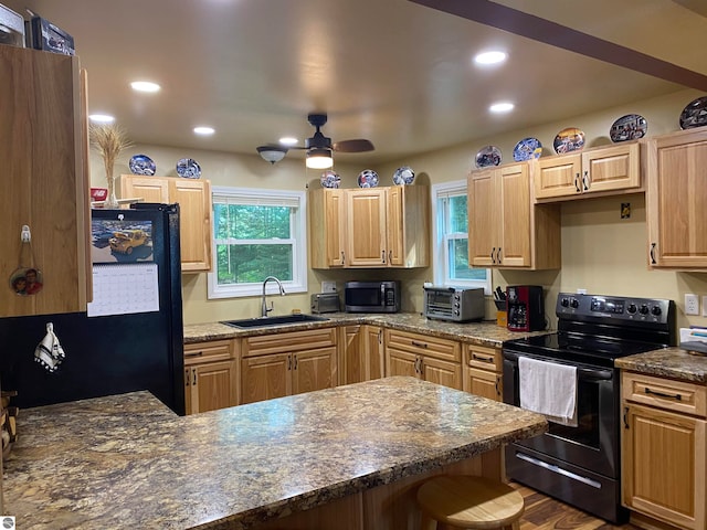 kitchen featuring a kitchen bar, black appliances, sink, and ceiling fan