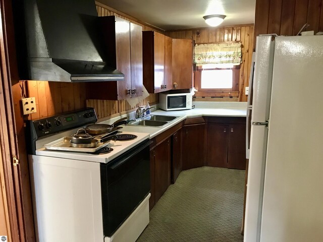 kitchen featuring wooden walls, ventilation hood, white appliances, and carpet flooring