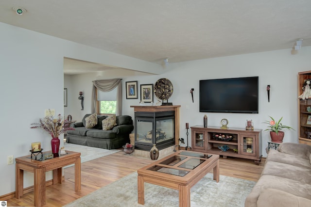 living room featuring light hardwood / wood-style flooring and a multi sided fireplace