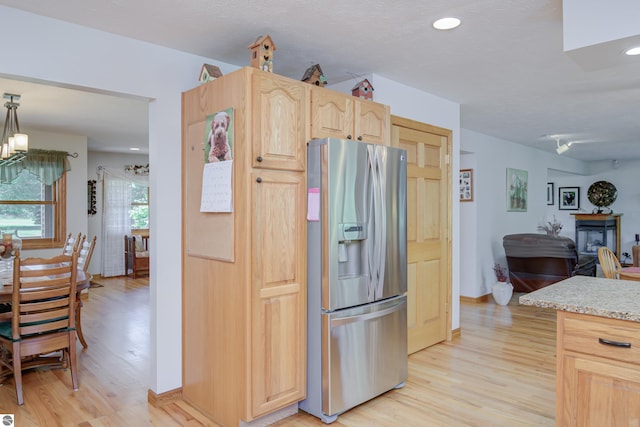 kitchen with pendant lighting, light brown cabinetry, stainless steel fridge, and light hardwood / wood-style floors