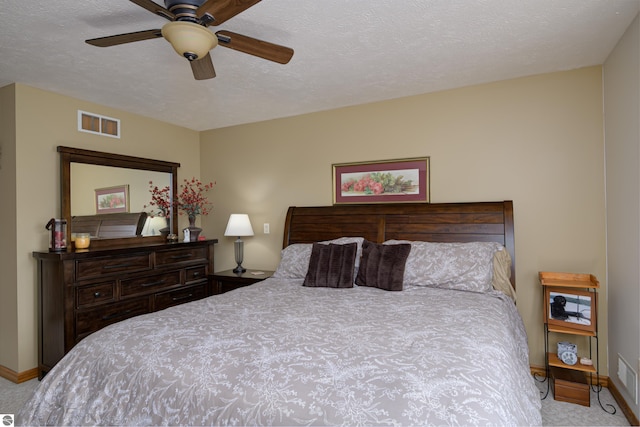 bedroom featuring ceiling fan, light colored carpet, and a textured ceiling