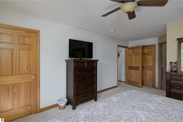 bedroom with ceiling fan, light colored carpet, and a textured ceiling