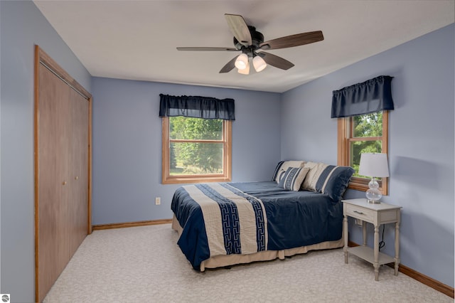 carpeted bedroom with ceiling fan and a closet