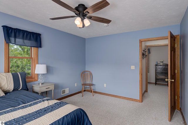 bedroom with ceiling fan, light colored carpet, and a textured ceiling