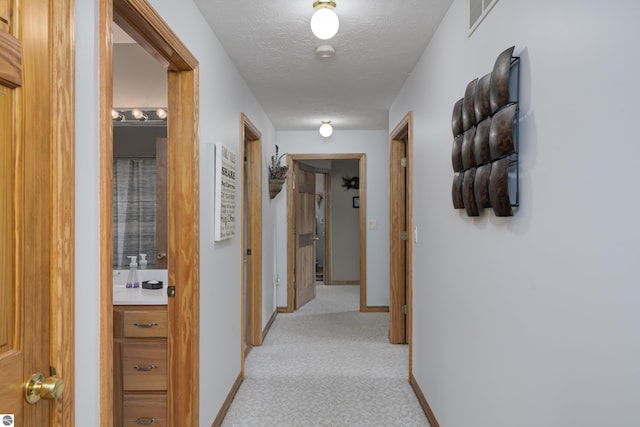 corridor featuring light carpet and a textured ceiling