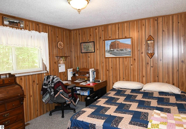 bedroom with wooden walls, a textured ceiling, and carpet flooring