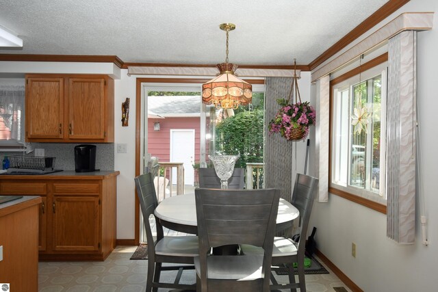 dining space featuring crown molding, a chandelier, and a textured ceiling