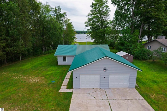 view of front facade featuring a garage, a water view, an outdoor structure, and a front lawn