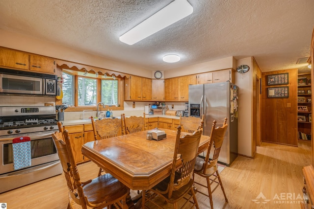 dining area with light wood finished floors, visible vents, and a textured ceiling