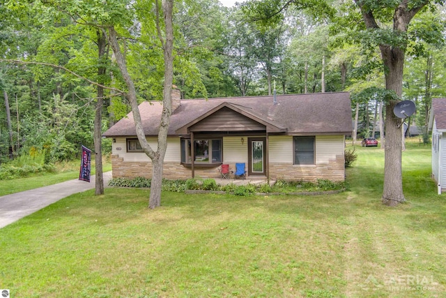 single story home featuring a porch, stone siding, driveway, a front lawn, and a chimney