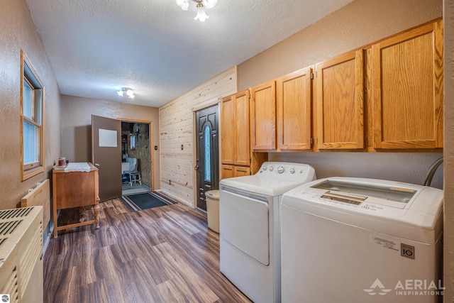 washroom featuring dark wood-style flooring, cabinet space, wooden walls, a textured ceiling, and separate washer and dryer