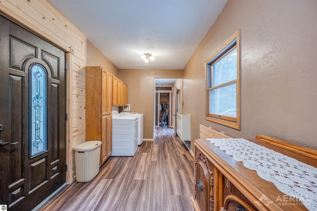 laundry area with a textured ceiling, a textured wall, dark wood-type flooring, and washer and clothes dryer