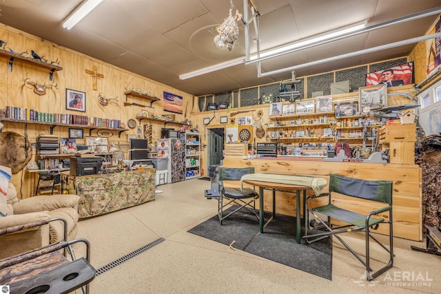 living room with speckled floor, wood walls, and a workshop area