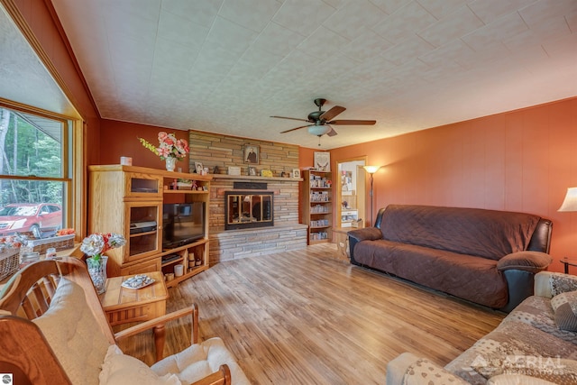 living area featuring wood walls, a fireplace, wood finished floors, and a ceiling fan