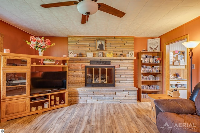 living area with ceiling fan, a fireplace, and wood finished floors