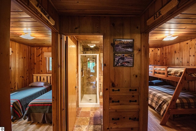 bedroom with light hardwood / wood-style flooring, wooden walls, and wood ceiling