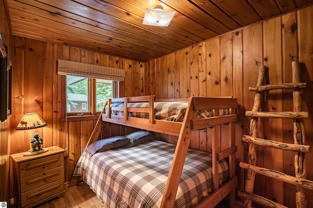 bedroom with light hardwood / wood-style flooring, wooden ceiling, and wooden walls