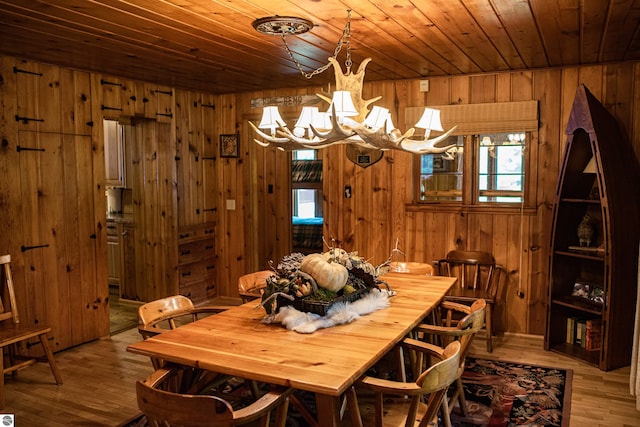 dining room with wooden ceiling, wooden walls, and light hardwood / wood-style floors