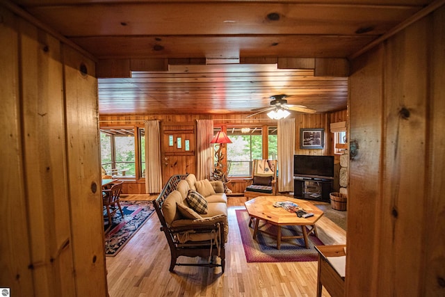 living room with light wood-type flooring, wooden walls, and wood ceiling