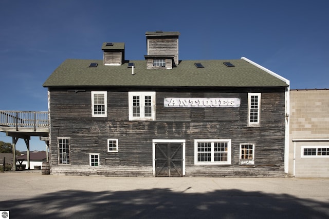 rear view of property featuring a shingled roof and a chimney