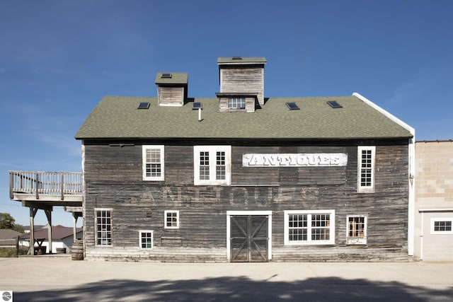 rear view of property with a shingled roof and a chimney