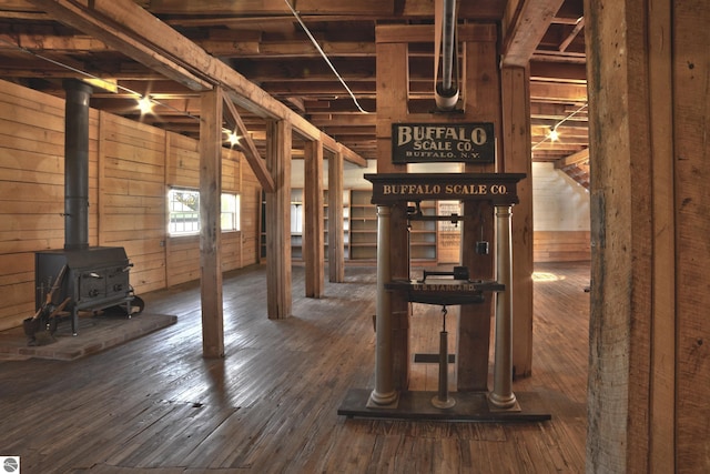 basement with a wood stove, wood walls, and hardwood / wood-style flooring