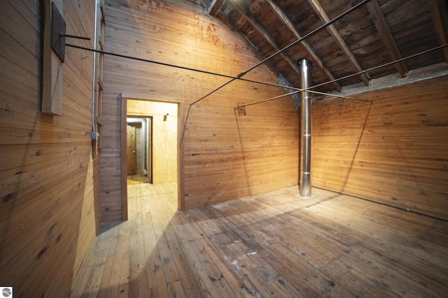 interior space with lofted ceiling with beams, wood ceiling, wooden walls, and wood-type flooring