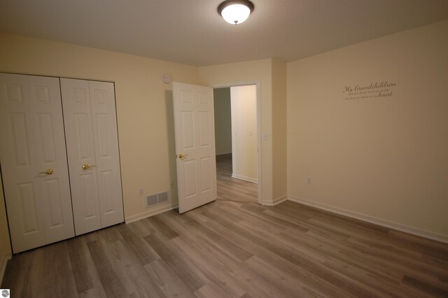 unfurnished bedroom featuring wood-type flooring and a closet