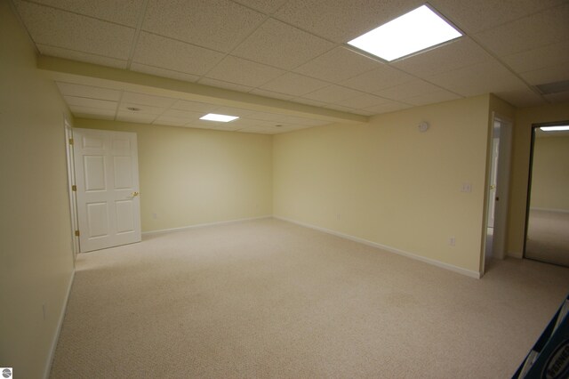 basement featuring a paneled ceiling and light colored carpet