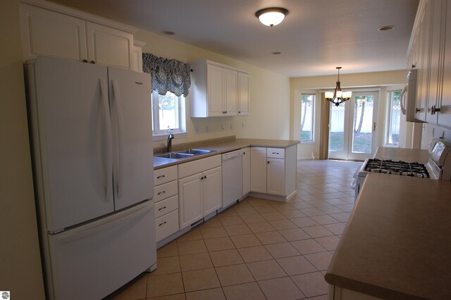 kitchen with white appliances, light tile patterned floors, white cabinets, sink, and a chandelier