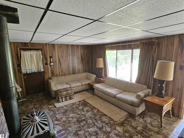 living room featuring a paneled ceiling and wooden walls