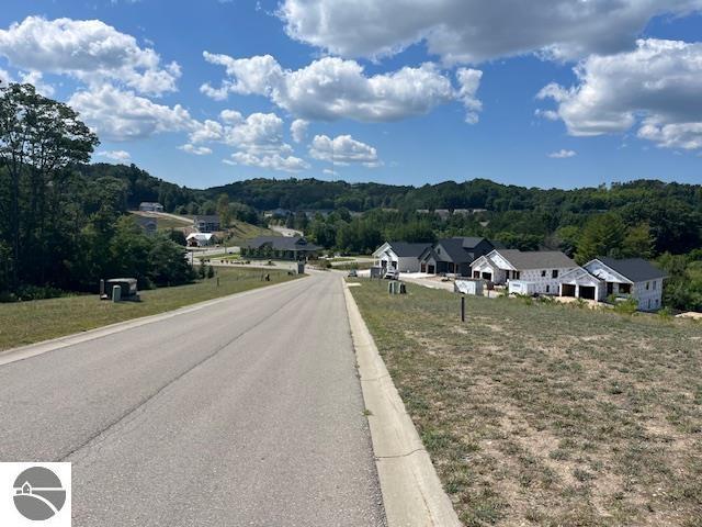 view of street featuring curbs, a wooded view, and a residential view