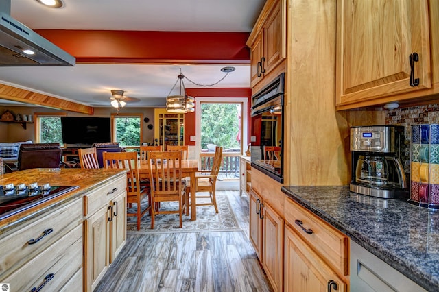 kitchen featuring hanging light fixtures, dark stone countertops, light hardwood / wood-style flooring, wall oven, and black gas stovetop