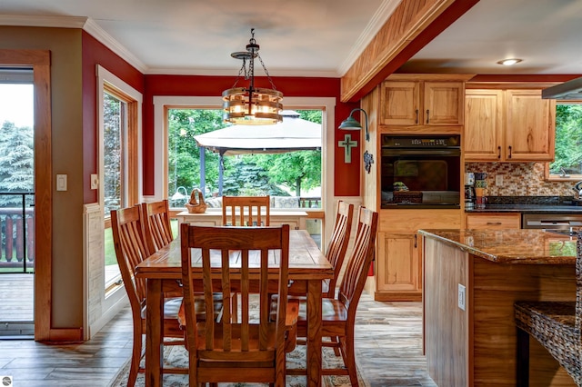 dining area featuring crown molding, a chandelier, and light wood-type flooring