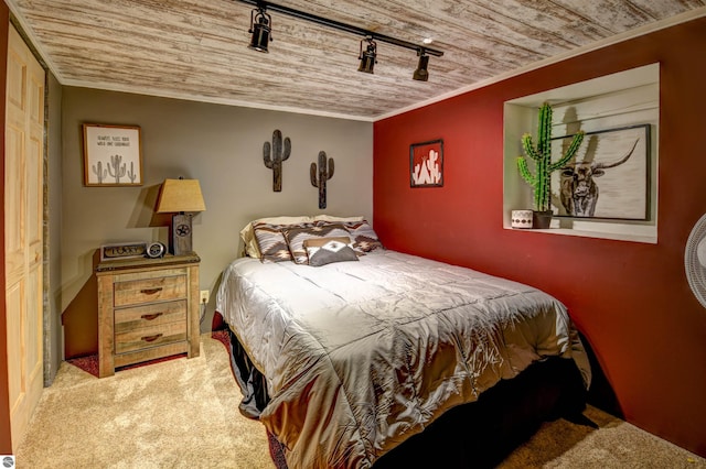 bedroom with wood ceiling, ornamental molding, rail lighting, and carpet