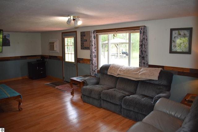 living room with an AC wall unit, wainscoting, and wood finished floors