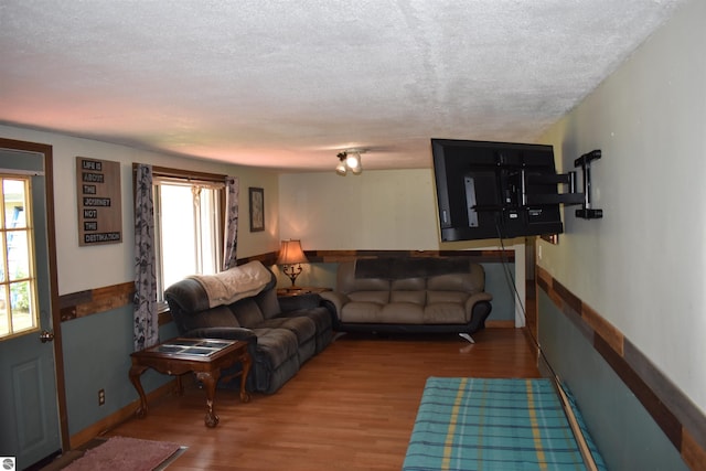 living area with a textured ceiling, wood finished floors, and baseboards