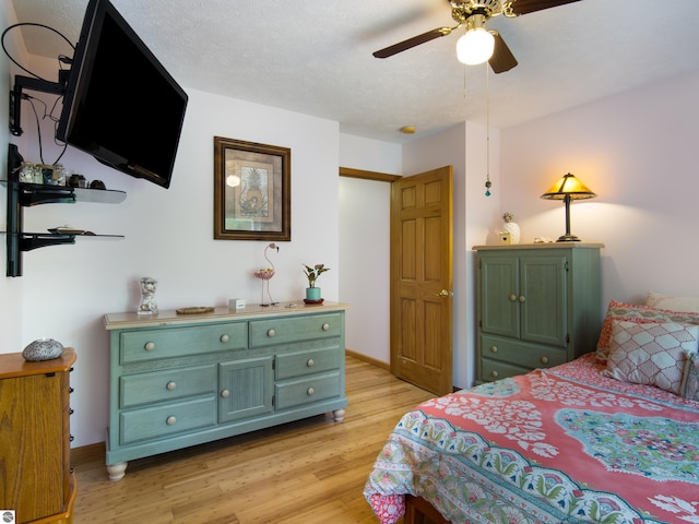 bedroom with ceiling fan, light wood-type flooring, and a textured ceiling