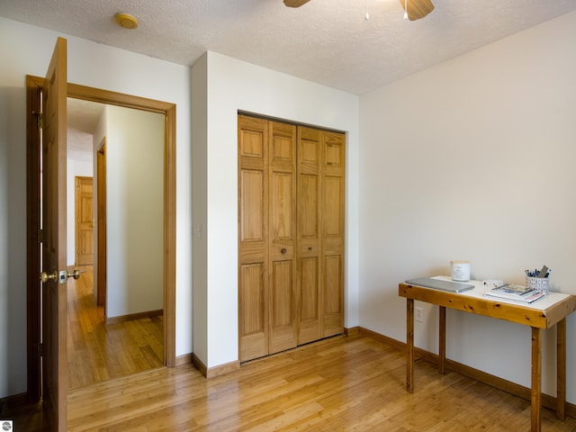 bedroom with ceiling fan, light hardwood / wood-style flooring, a textured ceiling, and a closet