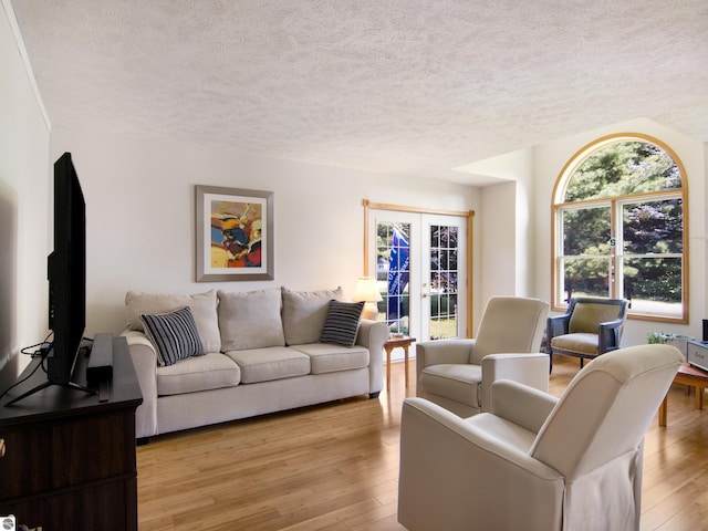 living room featuring light wood-type flooring, french doors, and a textured ceiling