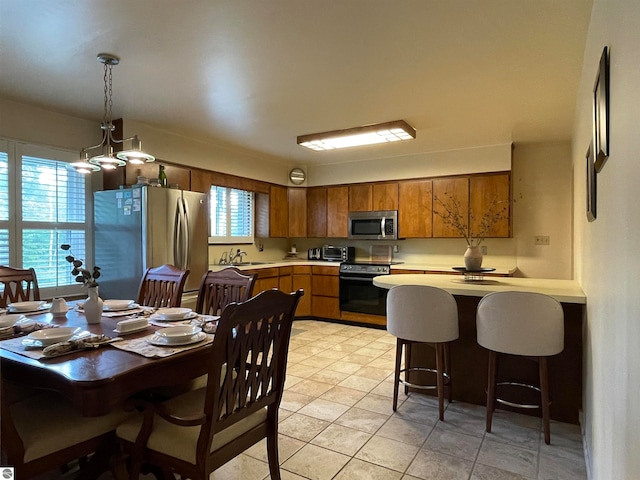 kitchen featuring appliances with stainless steel finishes, light tile patterned floors, sink, and pendant lighting