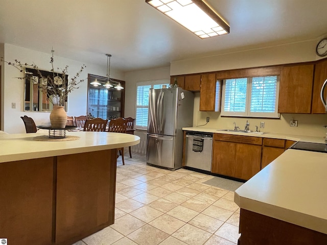 kitchen with light tile patterned flooring, stainless steel appliances, sink, and decorative light fixtures