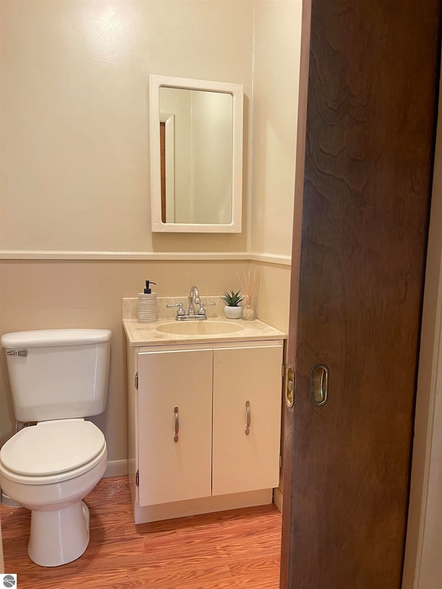 bathroom featuring wood-type flooring, vanity, and toilet