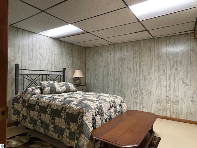 bedroom with wood walls, a paneled ceiling, and carpet floors